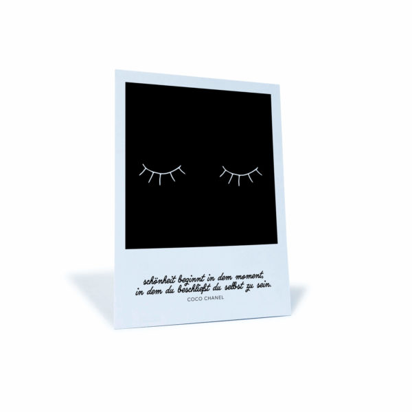 schwarz-weiße Postkarte mit Wimpern-Motiv und dem Spruch "Schönheit beginnt in dem Moment, in dem du beschließt du selbst zu sein"