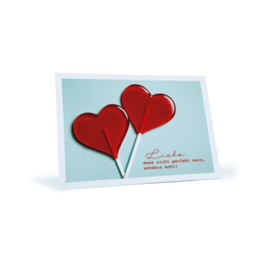 Liebes-Postkarte mit zwei roten Herz-Lutschern "Liebe muss nicht perfekt sein, sondern echt!"