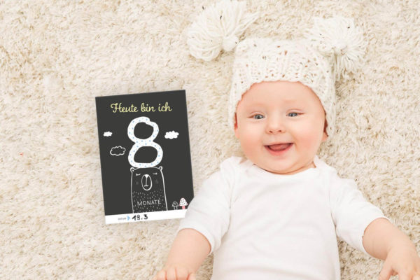 Baby mit Meilensteinkarte "Heute bin ich 8 Monate"